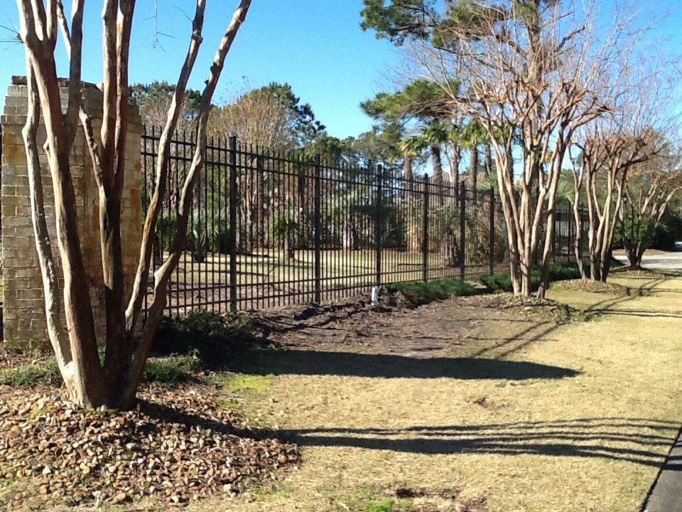 A fence surrounds a grassy area with trees in the background