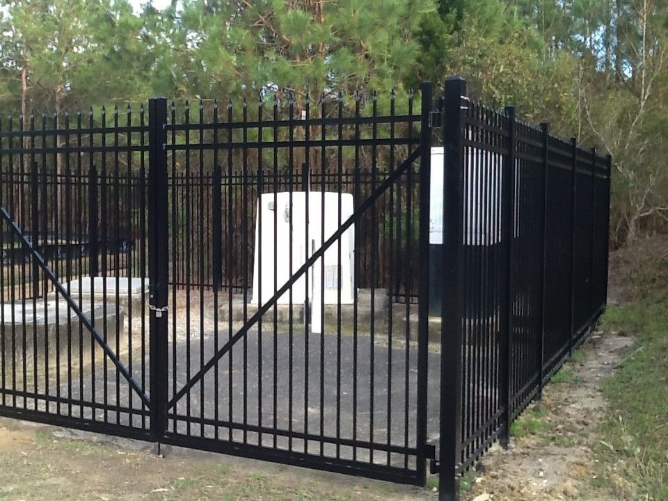A black metal fence surrounds a white building