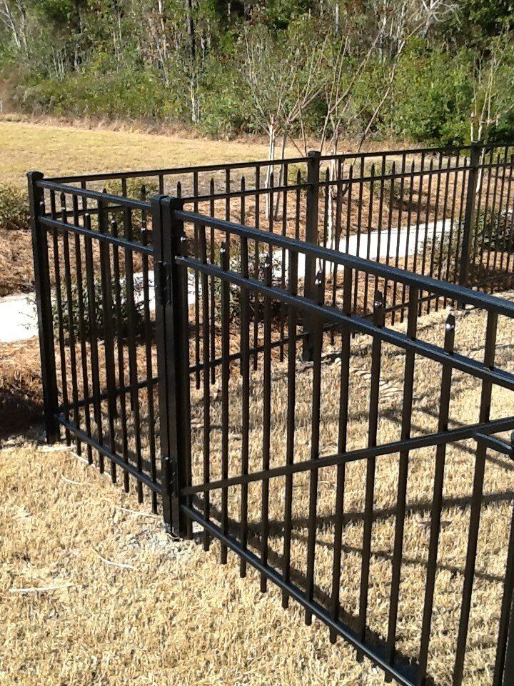 A black metal fence surrounds a lush green lawn