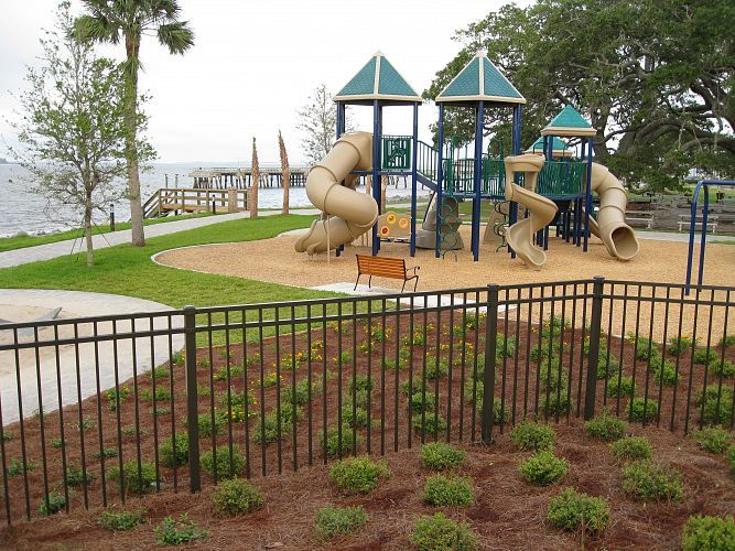 A playground with a fence and a bench in front of it