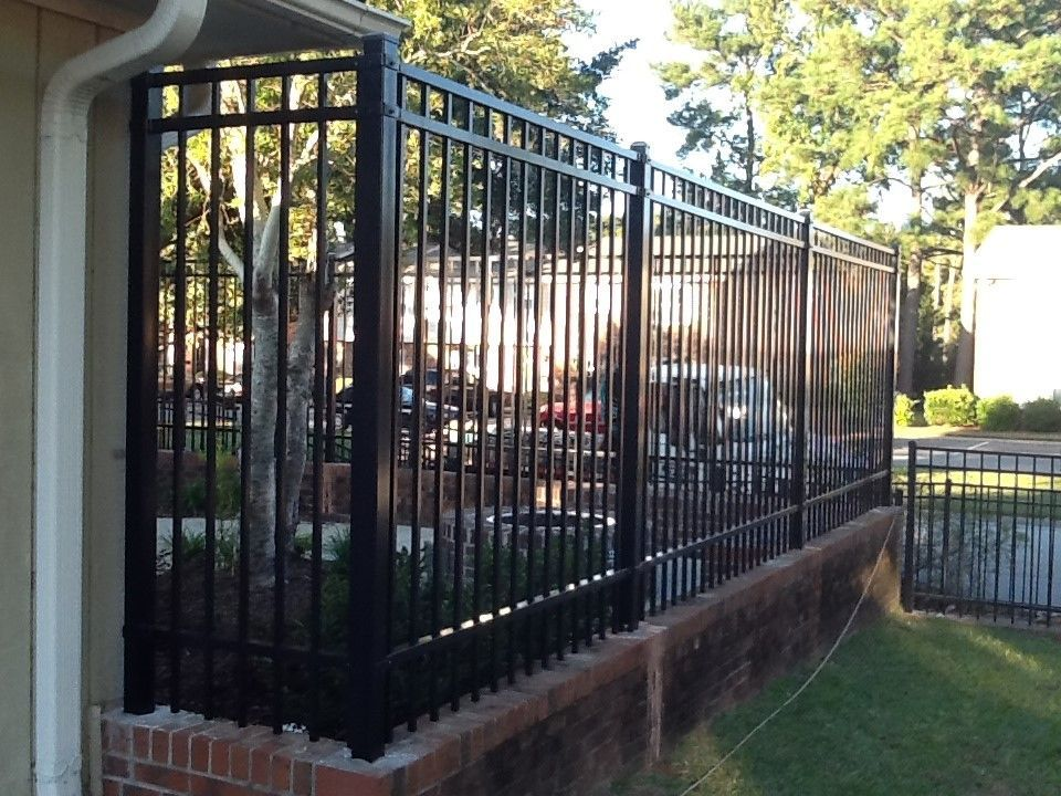 A wrought iron gate is in front of a brick building.
