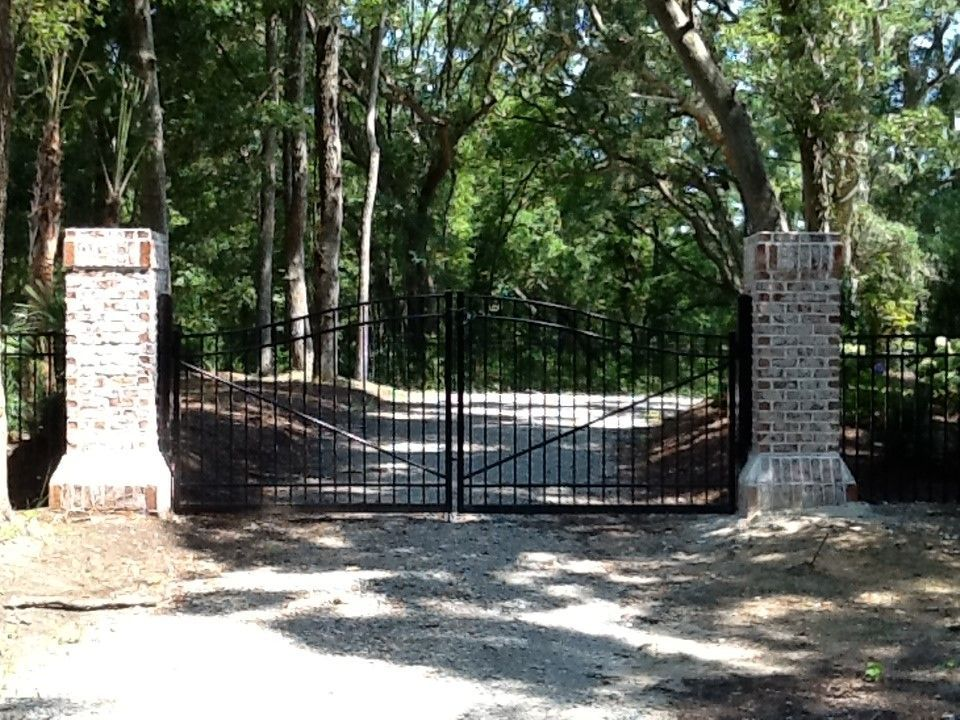 A black gate with a brick pillar in front of it