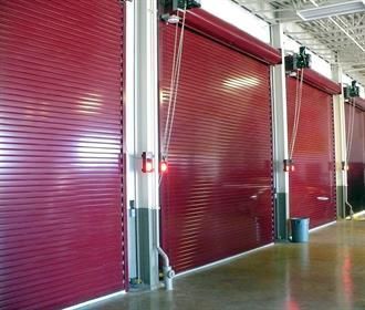 Row of red industrial roll-up doors in a warehouse corridor