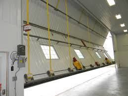 Industrial workspace with yellow hanging cables and workers beside a tilted wall panel