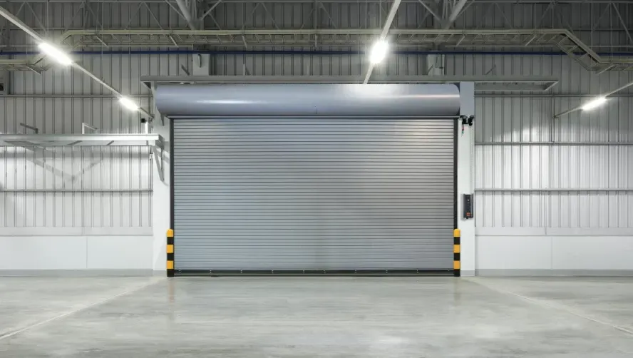 Closed gray roll-up warehouse door in an empty industrial loading bay