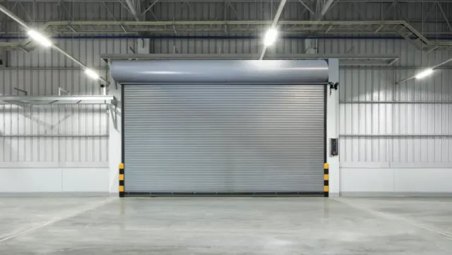 Empty warehouse interior with a large closed gray roll-up door and polished concrete floor