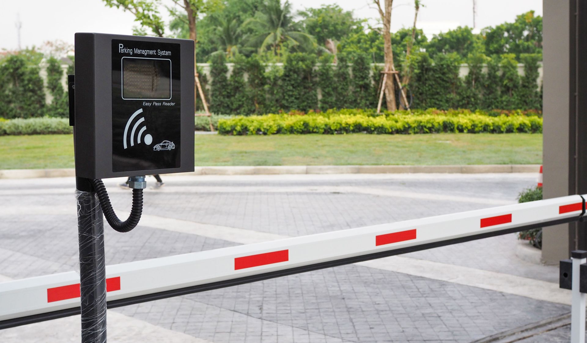 Parking lot entry barrier with black RFID card reader and red-and-white gate arm