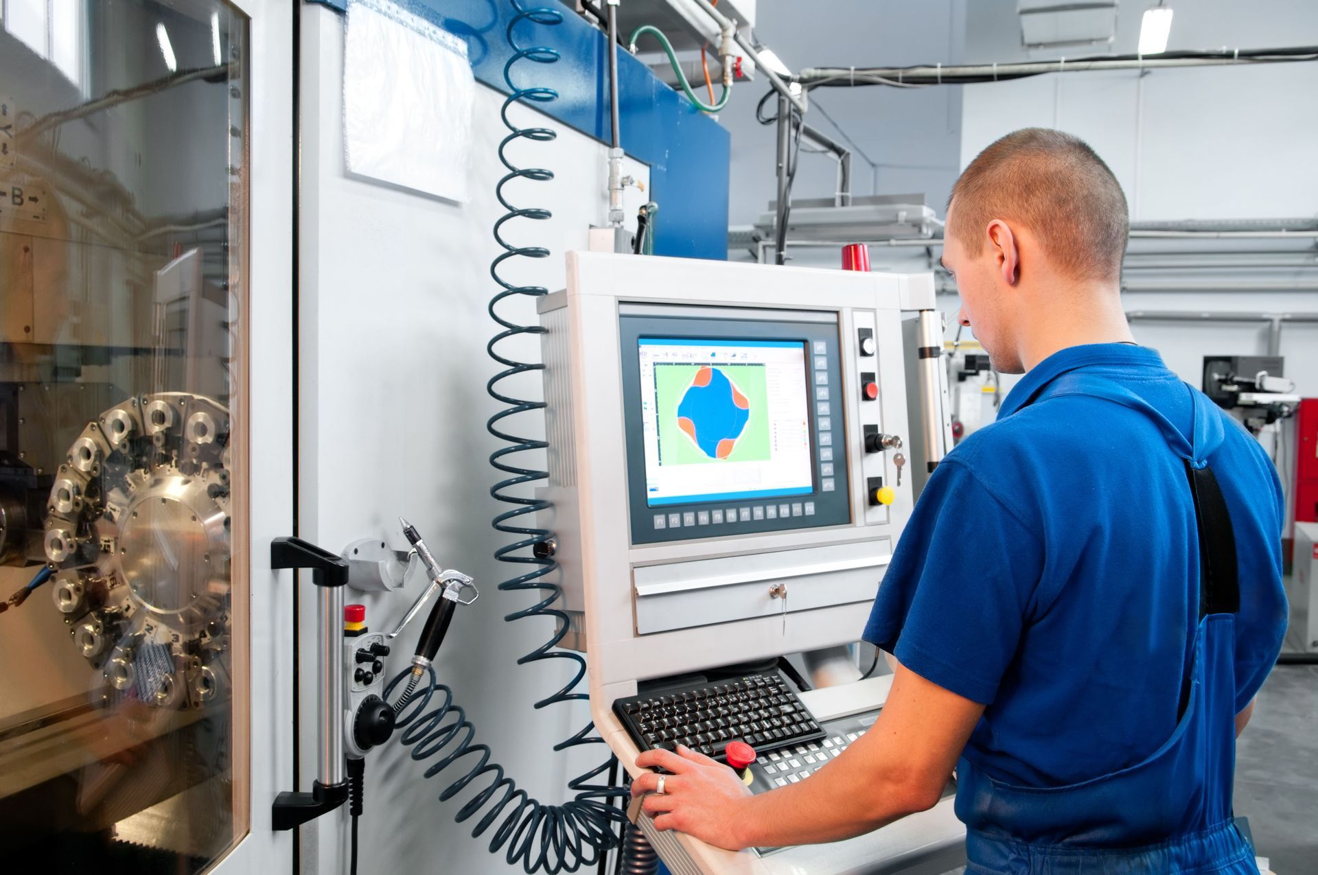 Technician operating a CNC machine control panel in a workshop