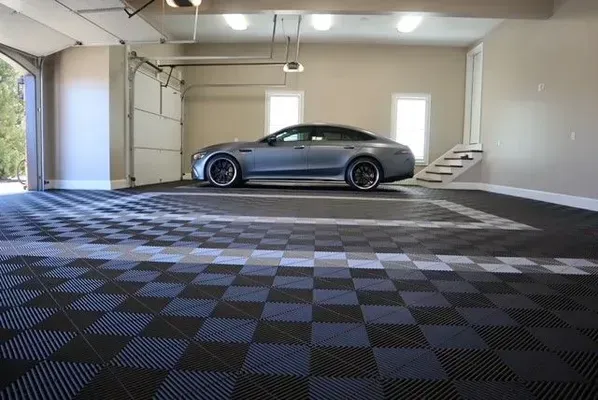 A silver luxury car parked inside a spacious garage with a black and blue checkered floor.