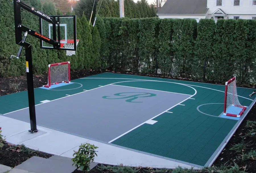 A backyard sports court features a green floor, a gray center with a letter