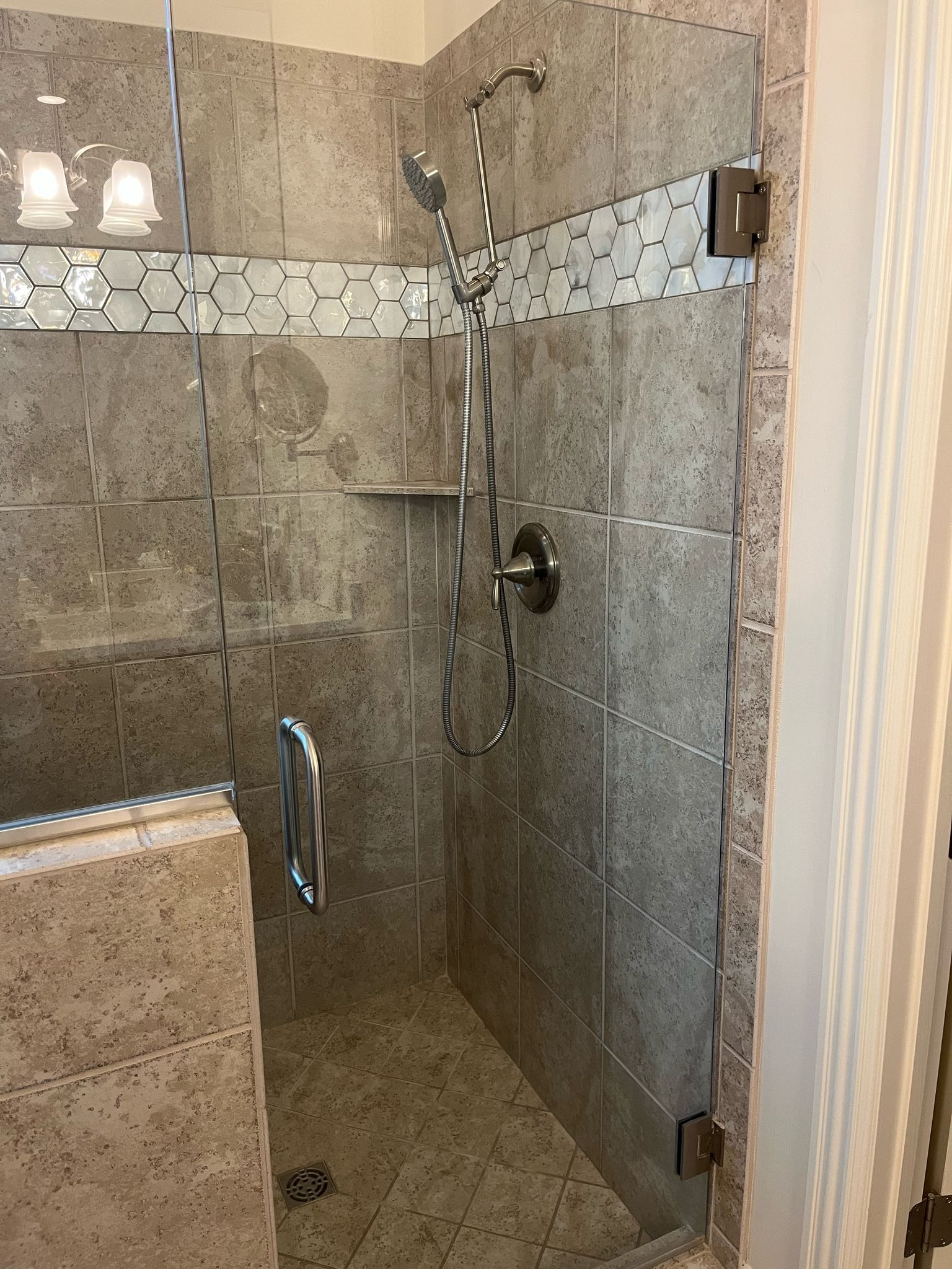 A bathroom with a walk in shower with a glass door.