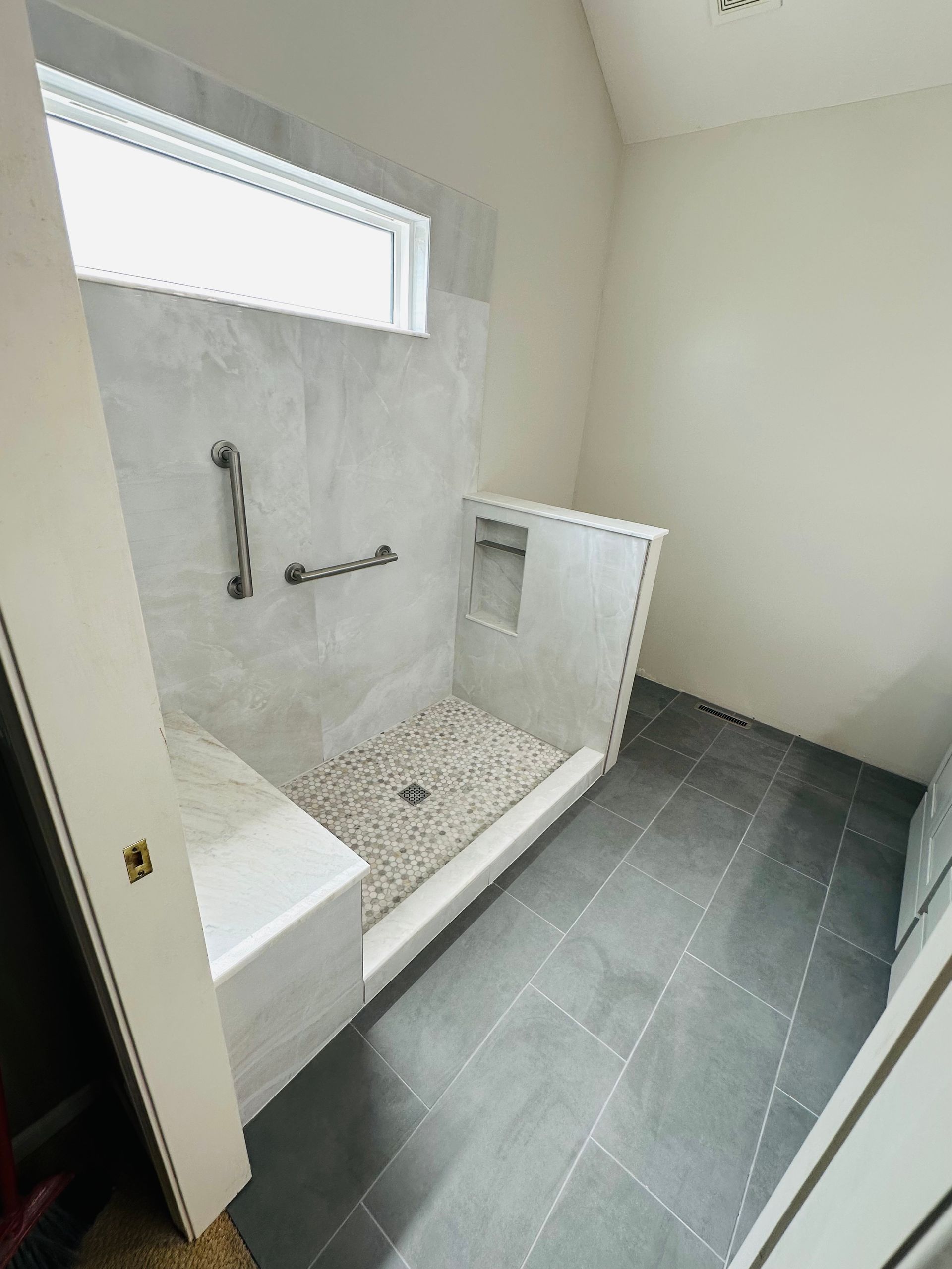 A bathroom with a walk in shower and a window.