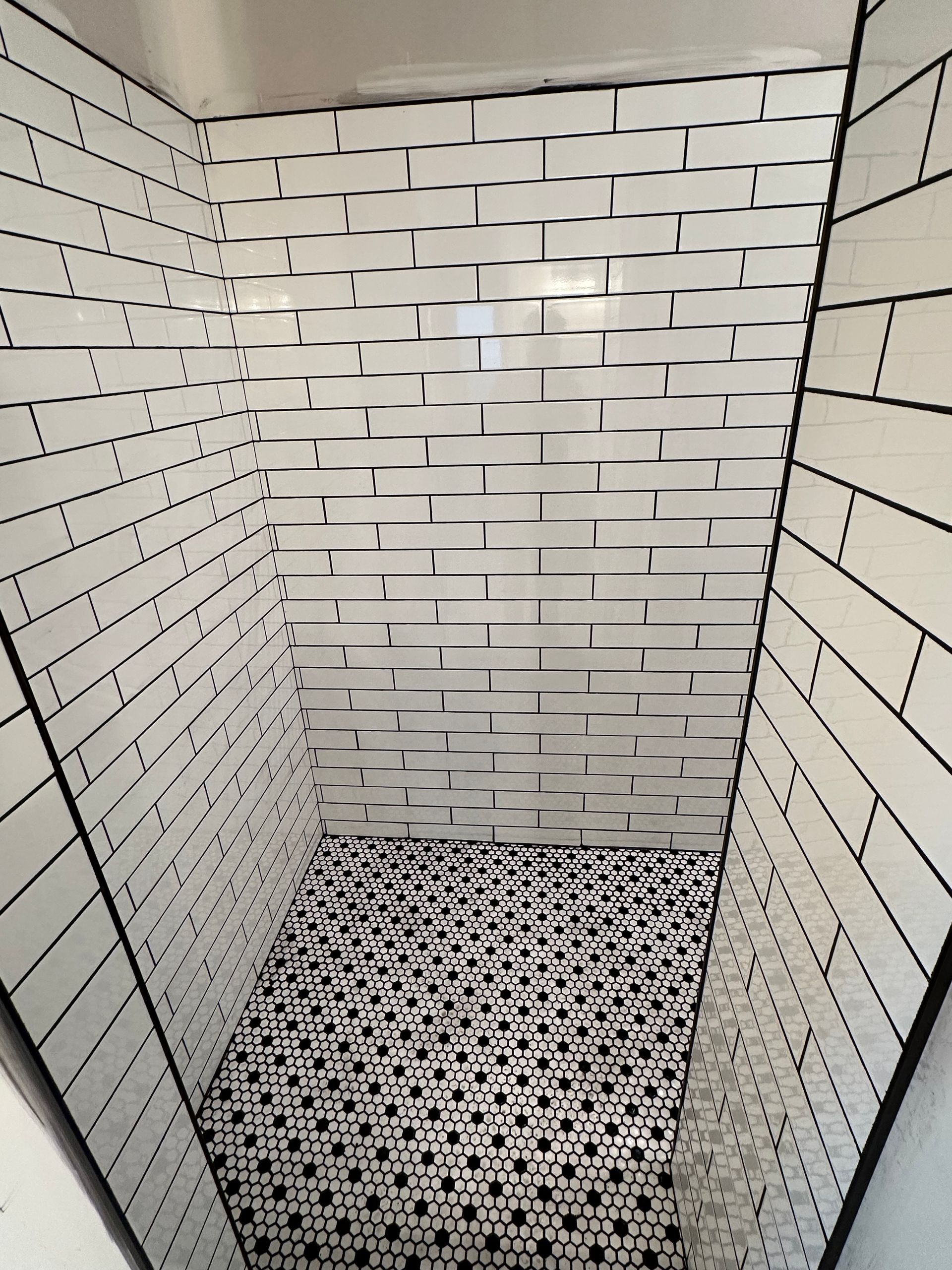 A bathroom with black and white tiles and a brick wall