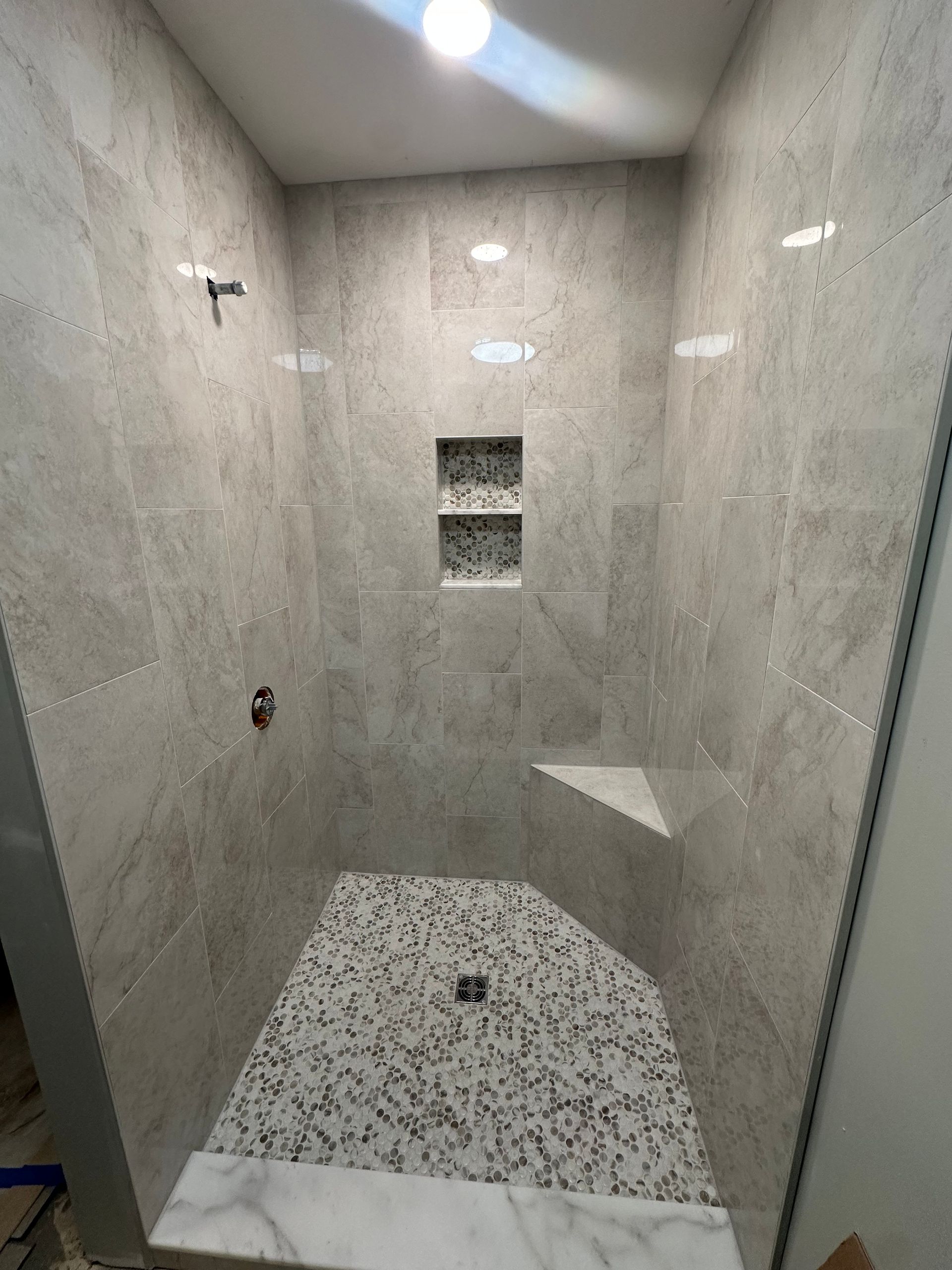 A bathroom with a walk in shower and a marble floor.
