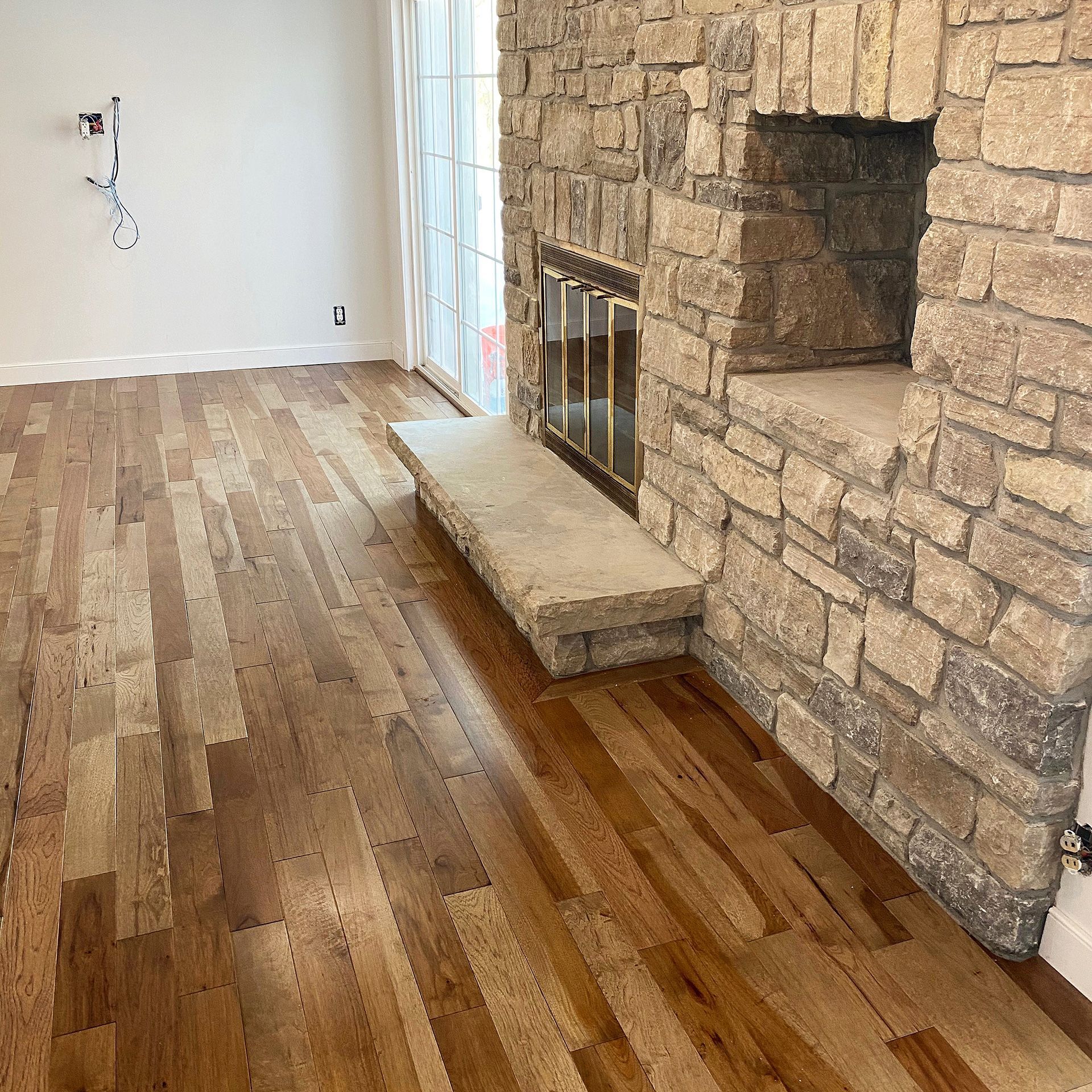 A living room with hardwood floors and a stone fireplace