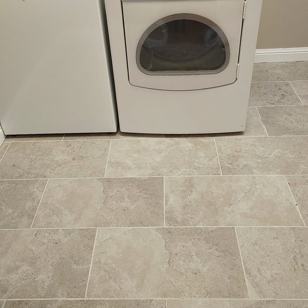 A washer and dryer are sitting on a tiled floor in a laundry room