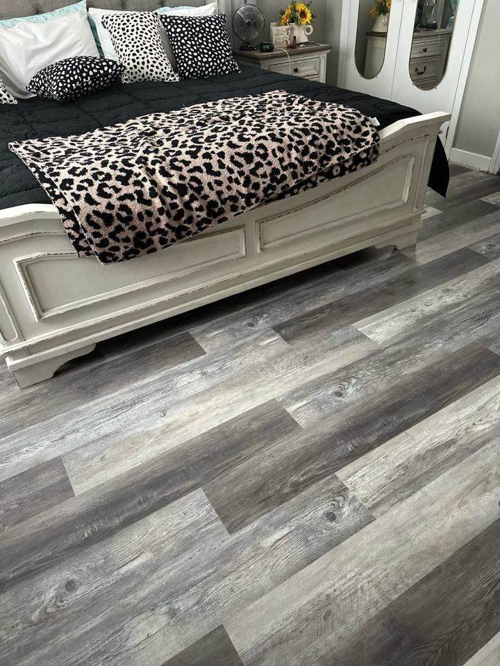 A bedroom with a bed and a leopard print blanket on the floor.