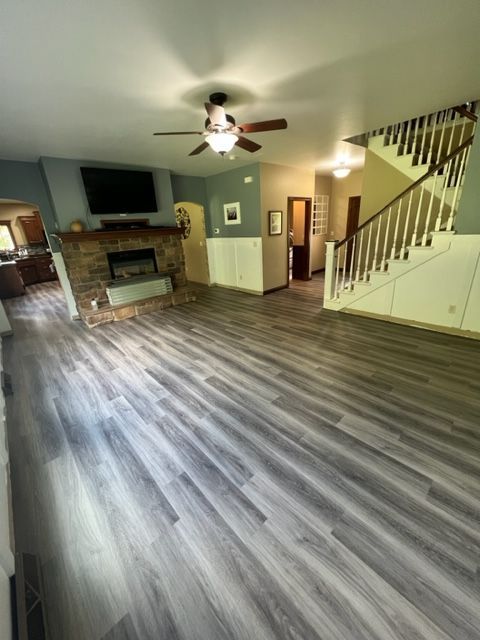 A living room with hardwood floors, a fireplace, and stairs
