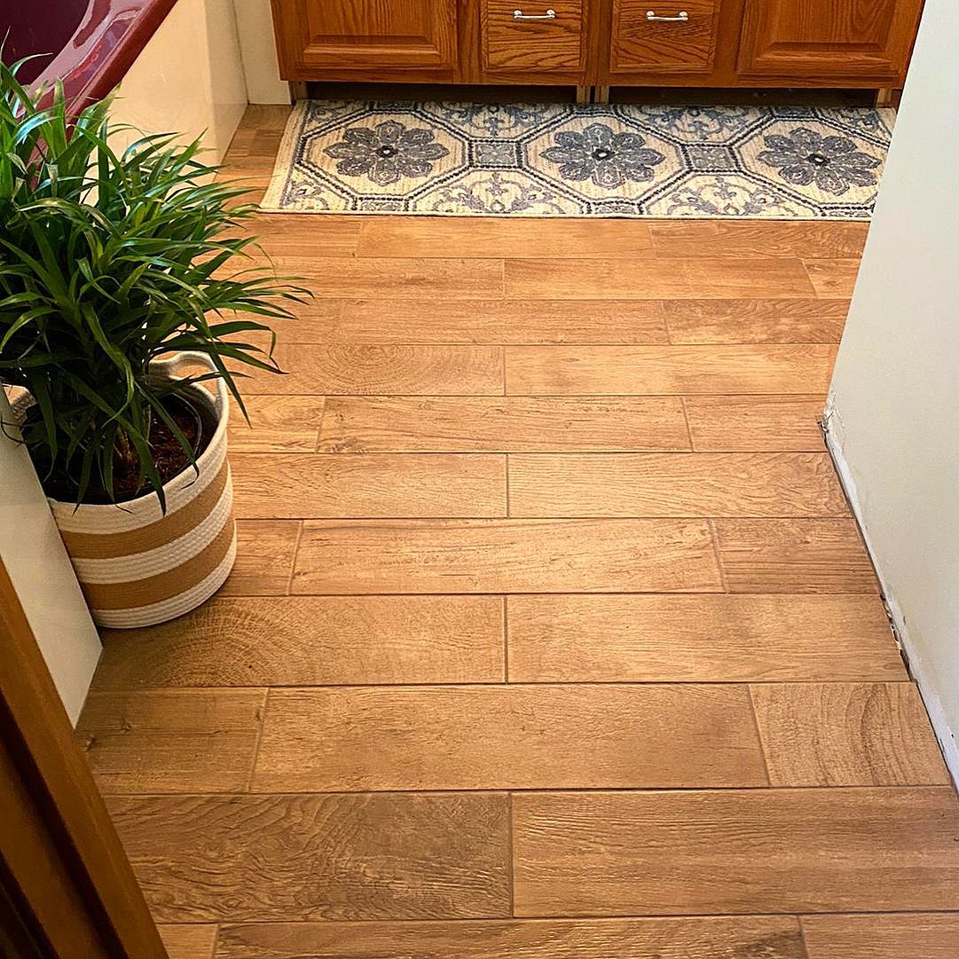 A potted plant is sitting on a wooden floor in a bathroom.