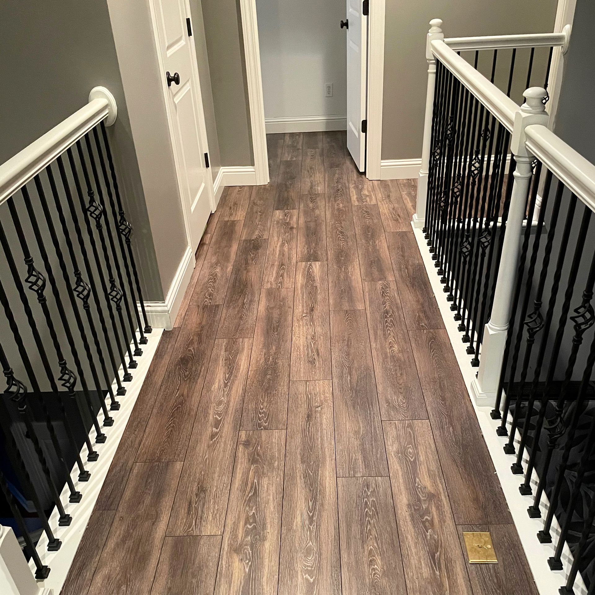 A hallway with wooden floors and a wrought iron railing