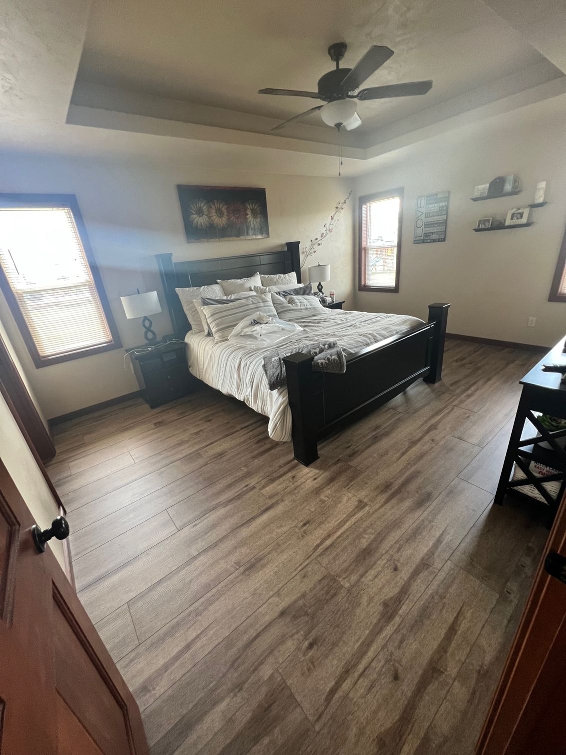A bedroom with a bed, ceiling fan, and hardwood floors