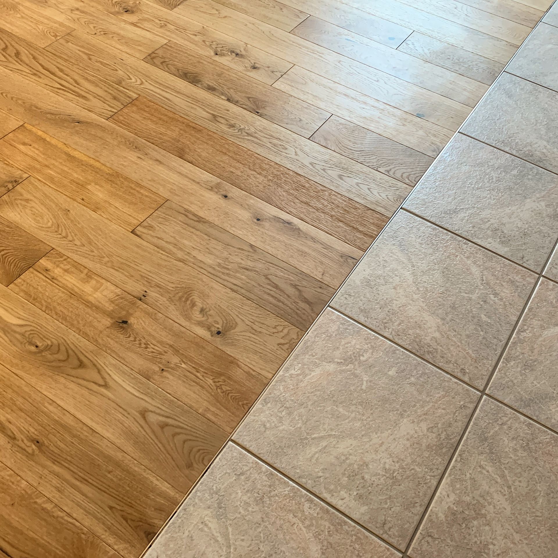 A close up of a wooden floor next to a tile floor