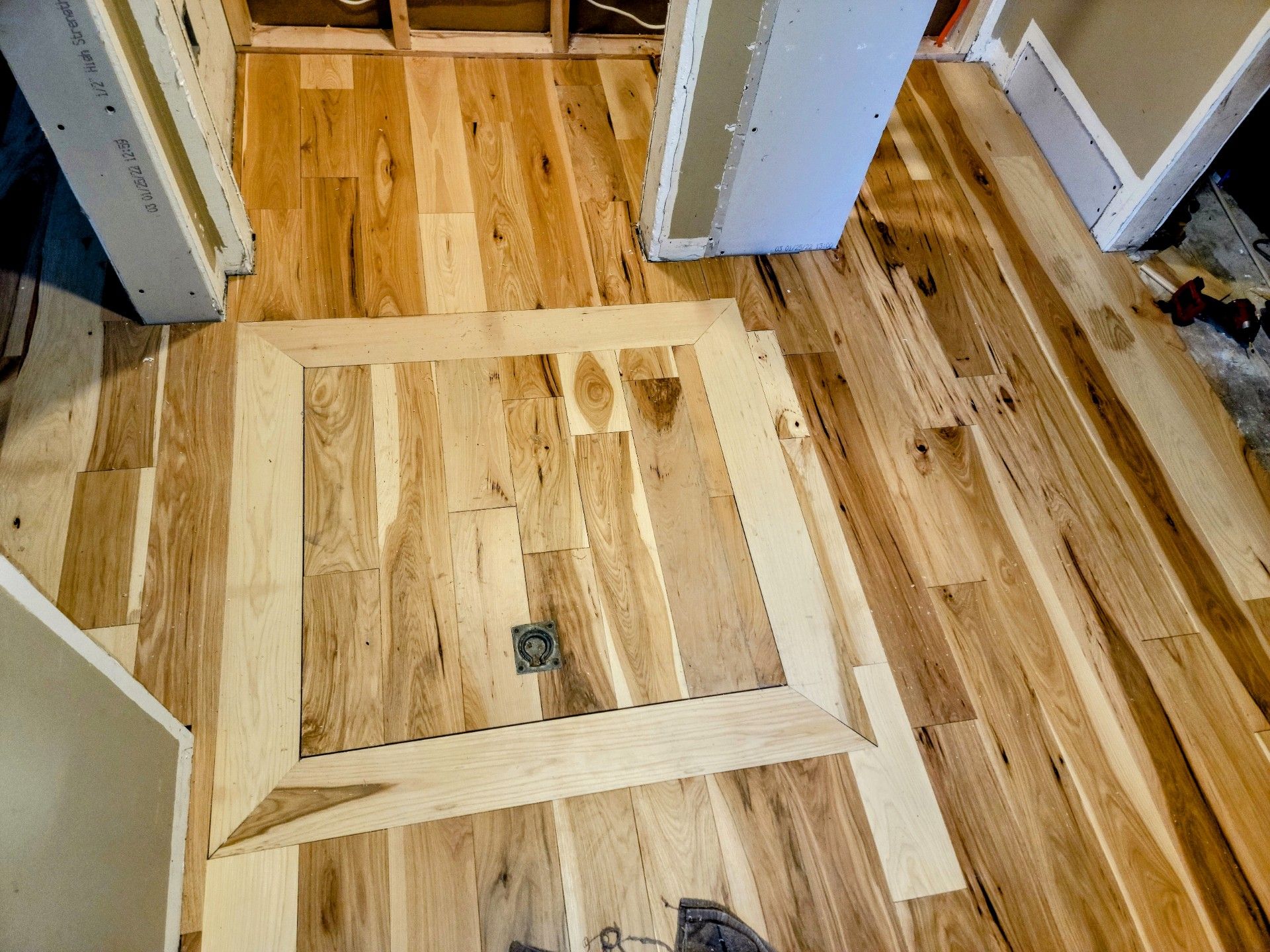 A wooden floor with a square hole in the middle of it.