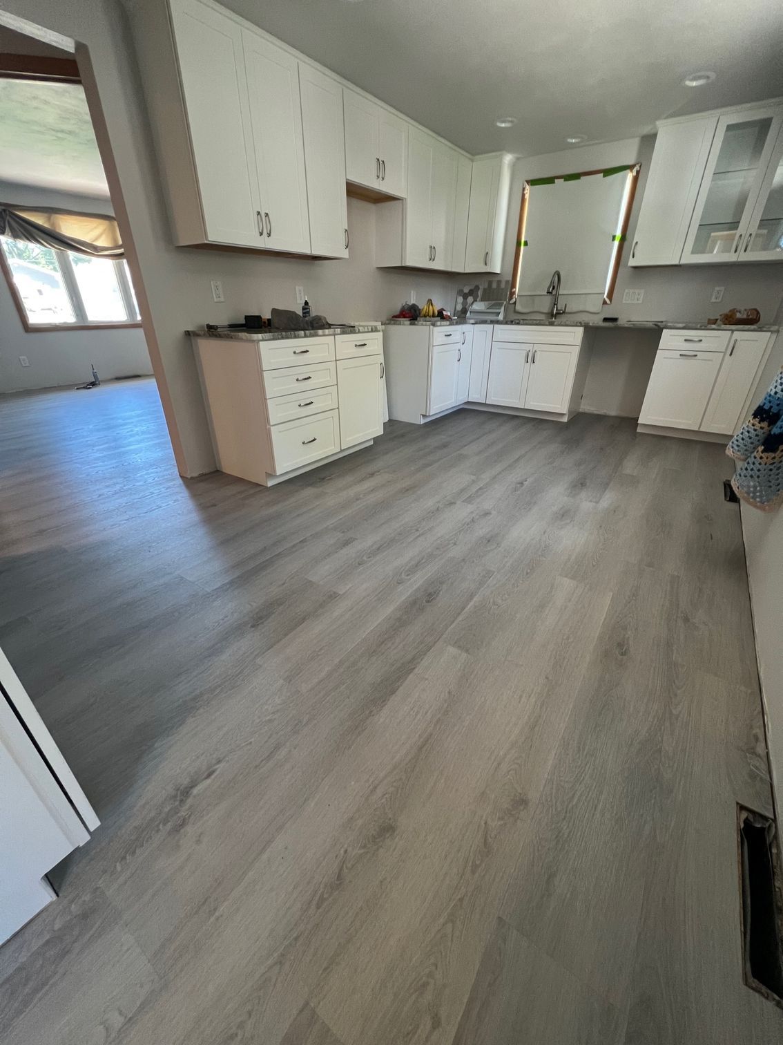 A kitchen with hardwood floors and white cabinets