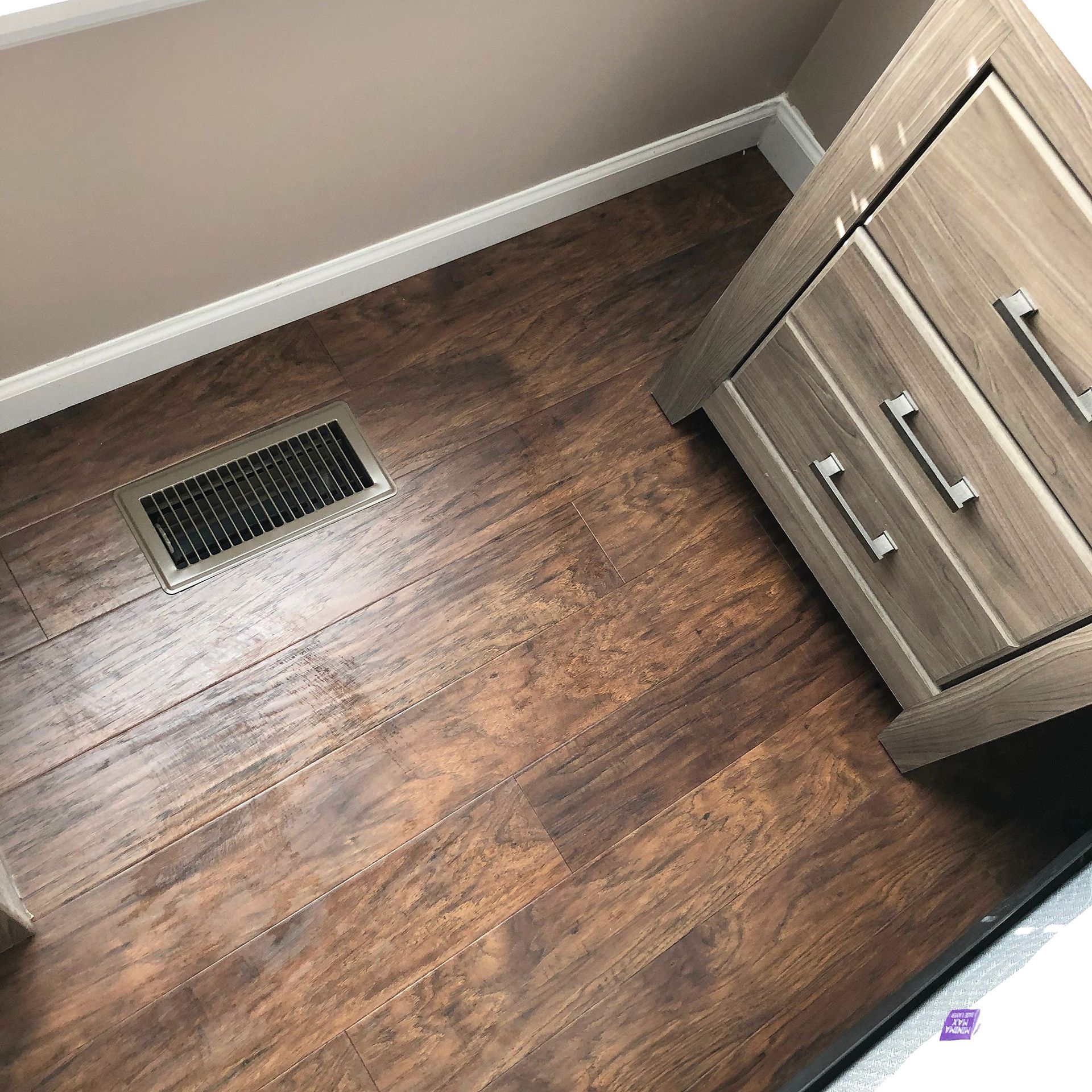 A room with hardwood floors, a dresser, and a window