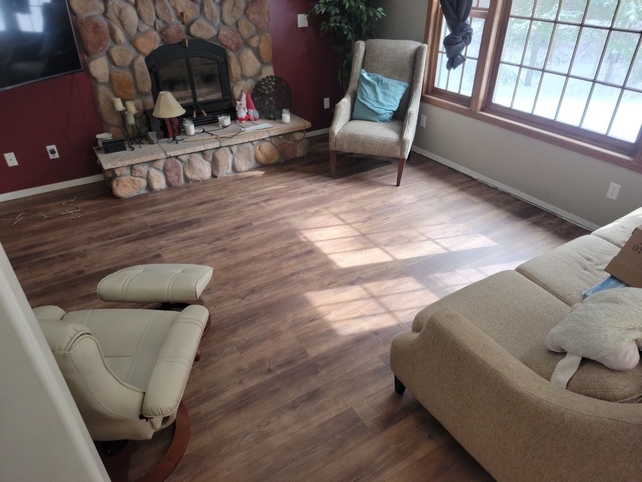 A living room with a fireplace, a couch, chairs, and hardwood floors