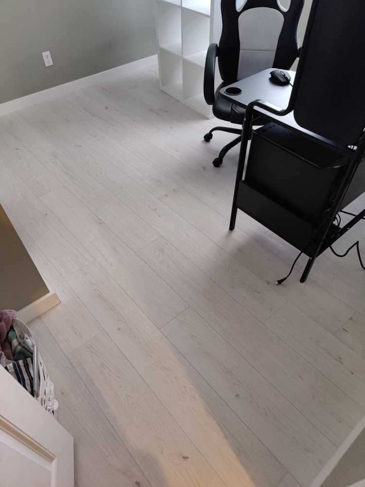 A white wooden floor with a black chair in a room