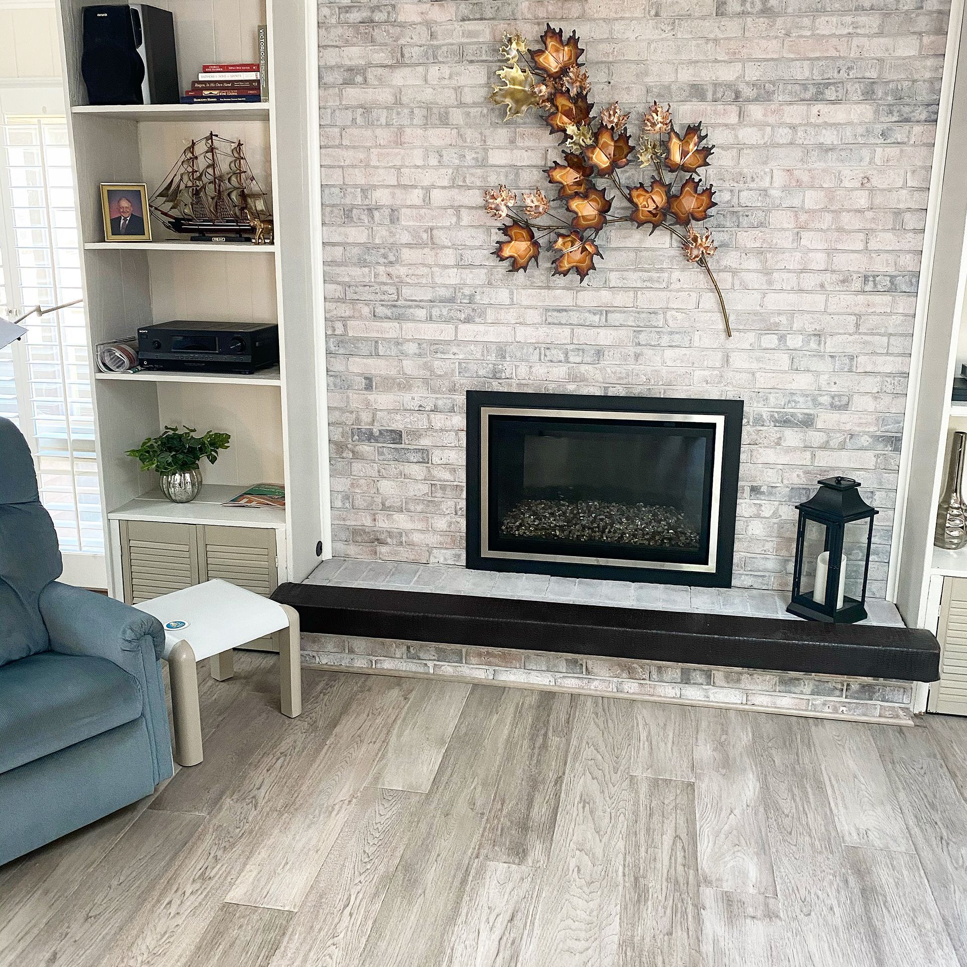 A living room with a fireplace, a chair and hardwood flooring