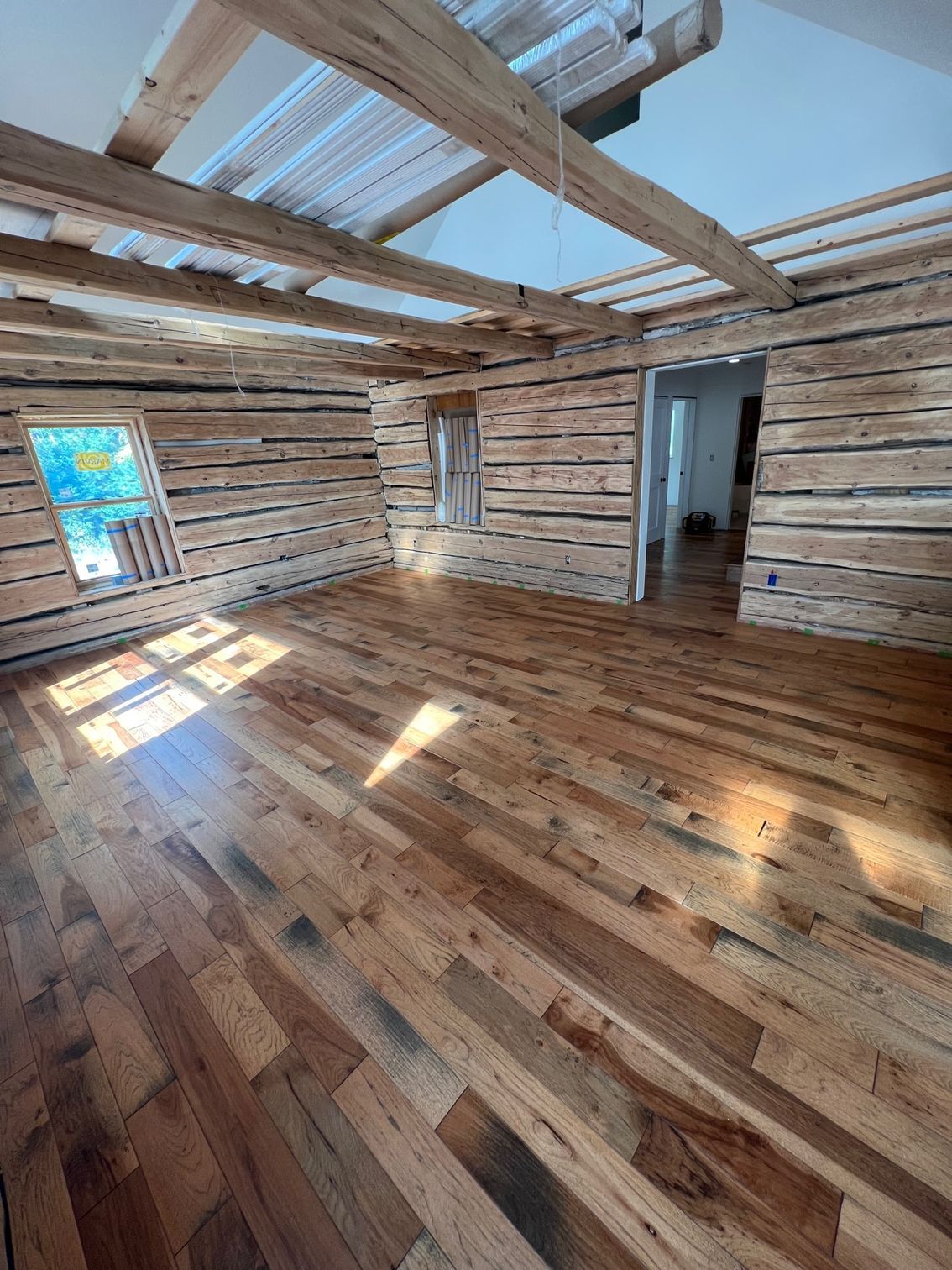 A spacious, empty room with hardwood flooring and wooden walls