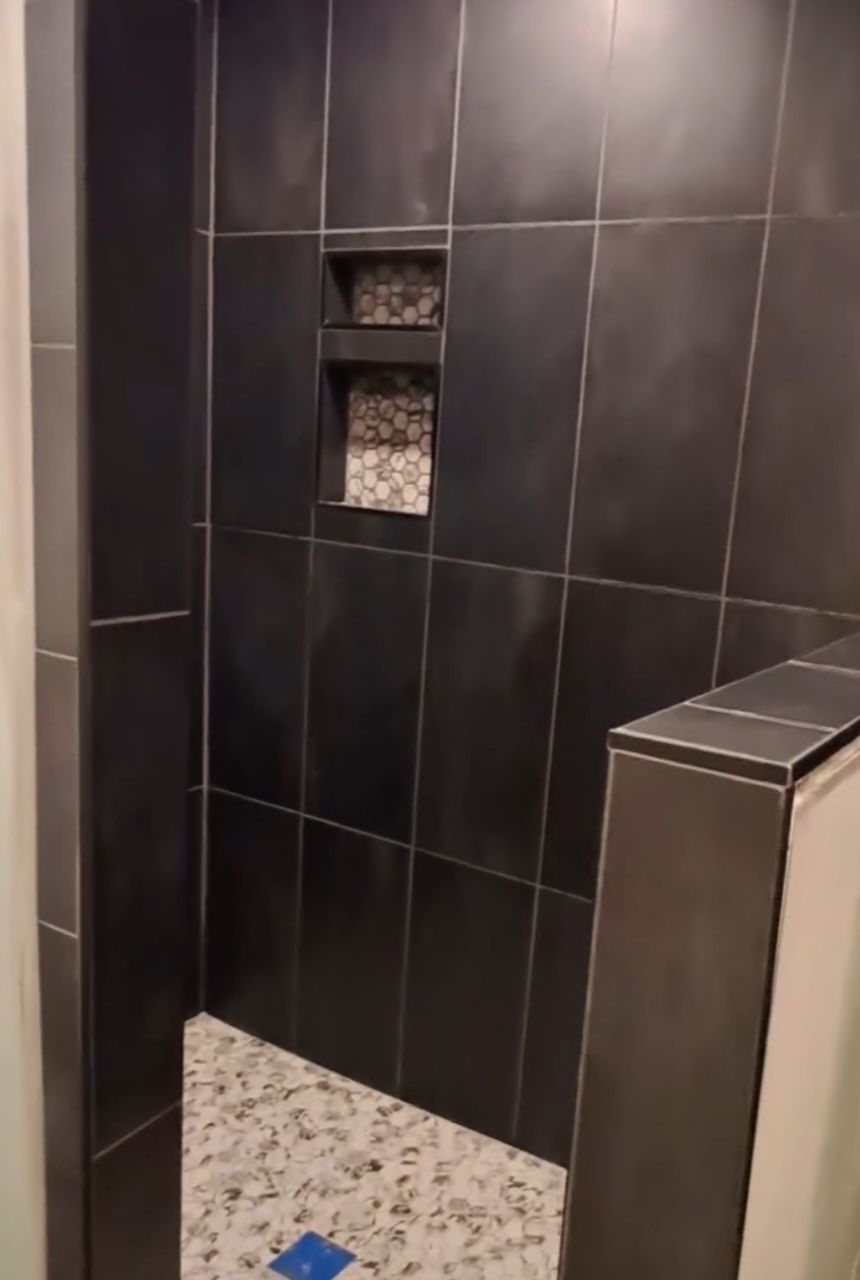 A bathroom with black tiles wall and white tiles floor