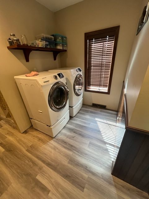 A laundry room with two washing machines and hardwood flooring