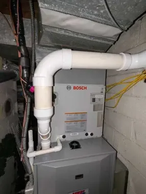 Bosch water heater with white PVC venting in a basement utility space