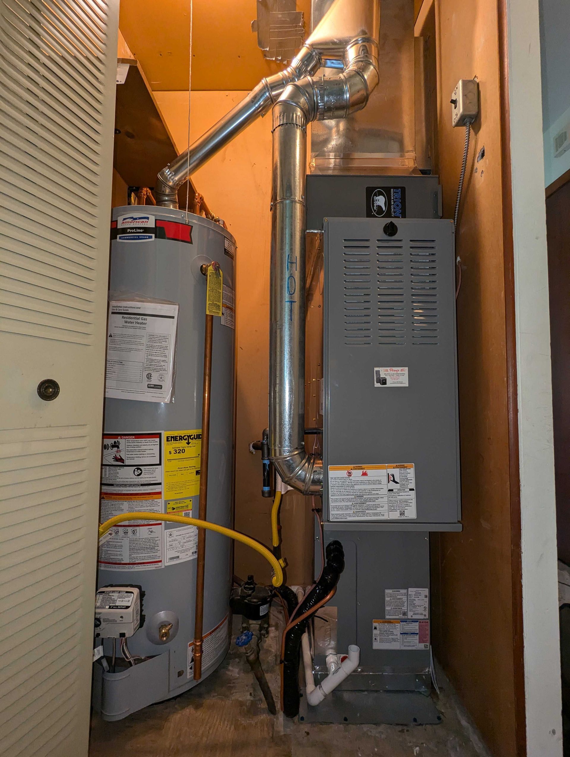 Water heater and furnace in a utility closet. The heater is on the left, furnace on the right, with metal ductwork.