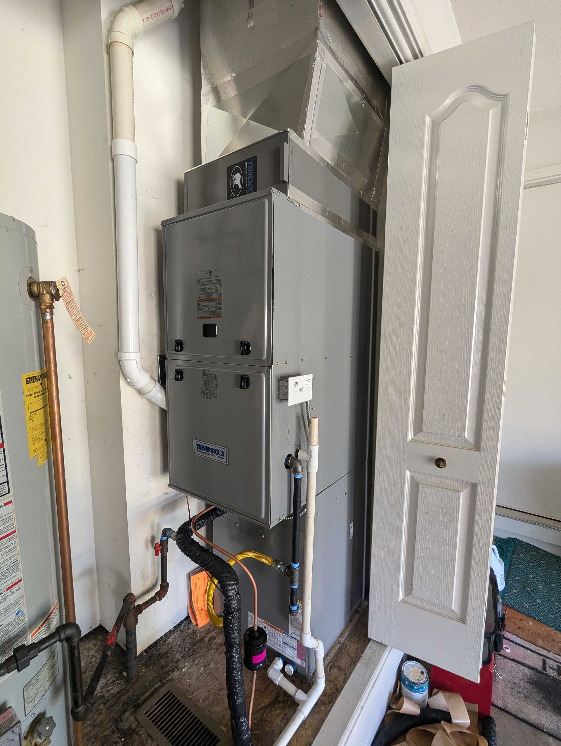 Gray furnace and water heater in a utility room next to a partially open door.
