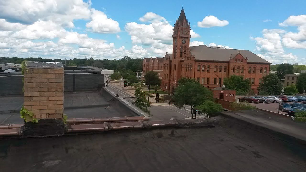 Brick building with clock tower under a blue sky with puffy white clouds.