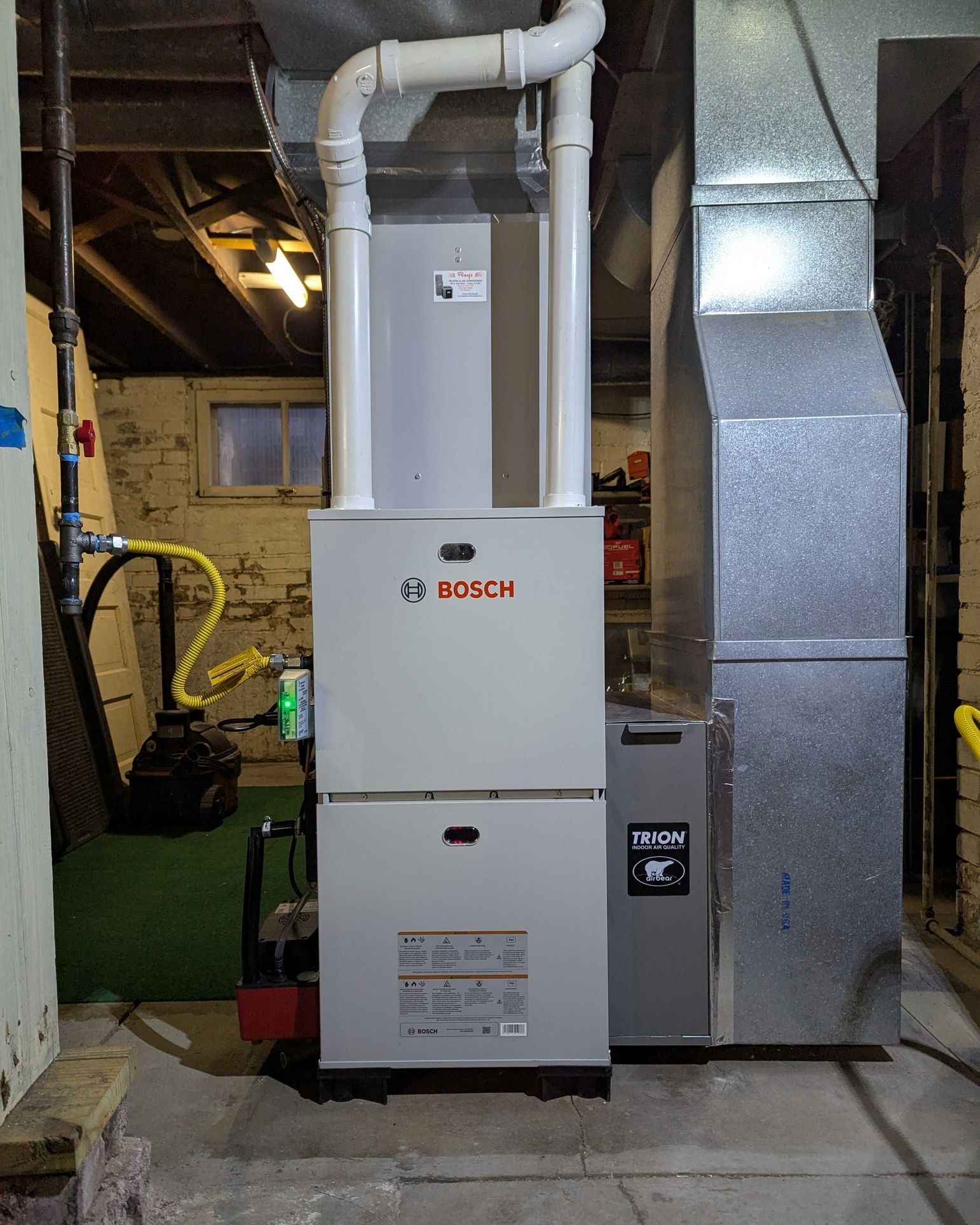 Bosch furnace in a basement; gray and white metal, with vents and gas lines.