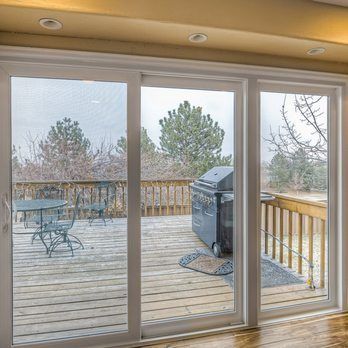 A room with sliding glass doors leading to a deck with a table and chairs