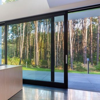A room with a view of a forest through a sliding glass door