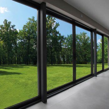 A large window with a view of a grassy field and trees