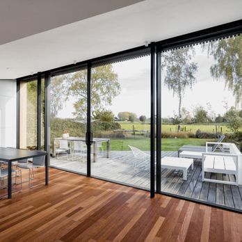 A living room with a table and chairs and a large window with a view of a field