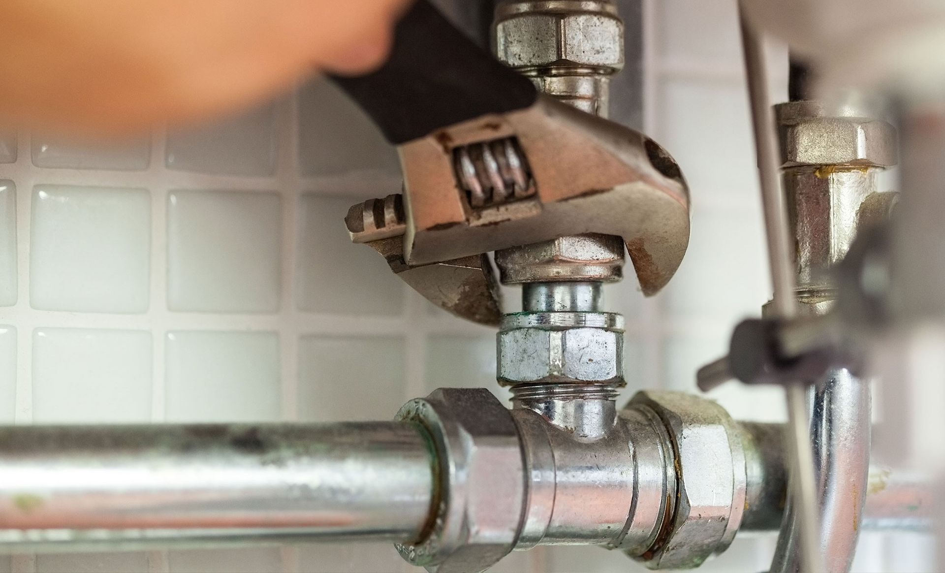 A person is fixing a pipe with a wrench.