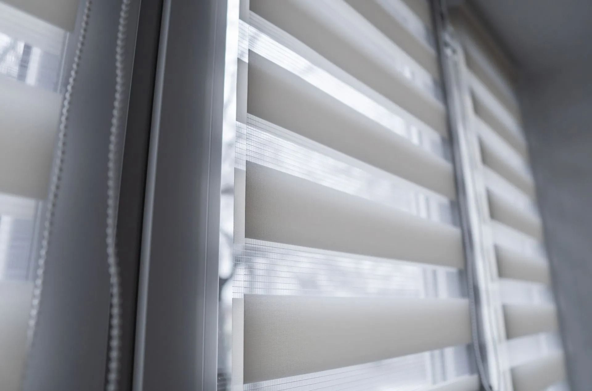 A close-up view of white, layered zebra blinds partially covering a window.