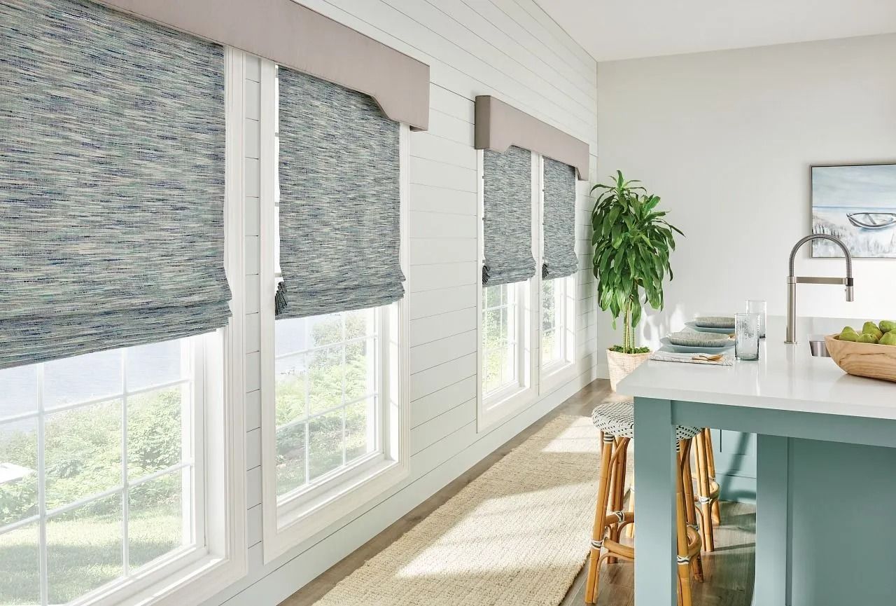 A bright kitchen with white shiplap walls, blue-toned woven window shades, a teal island, and a potted plant.