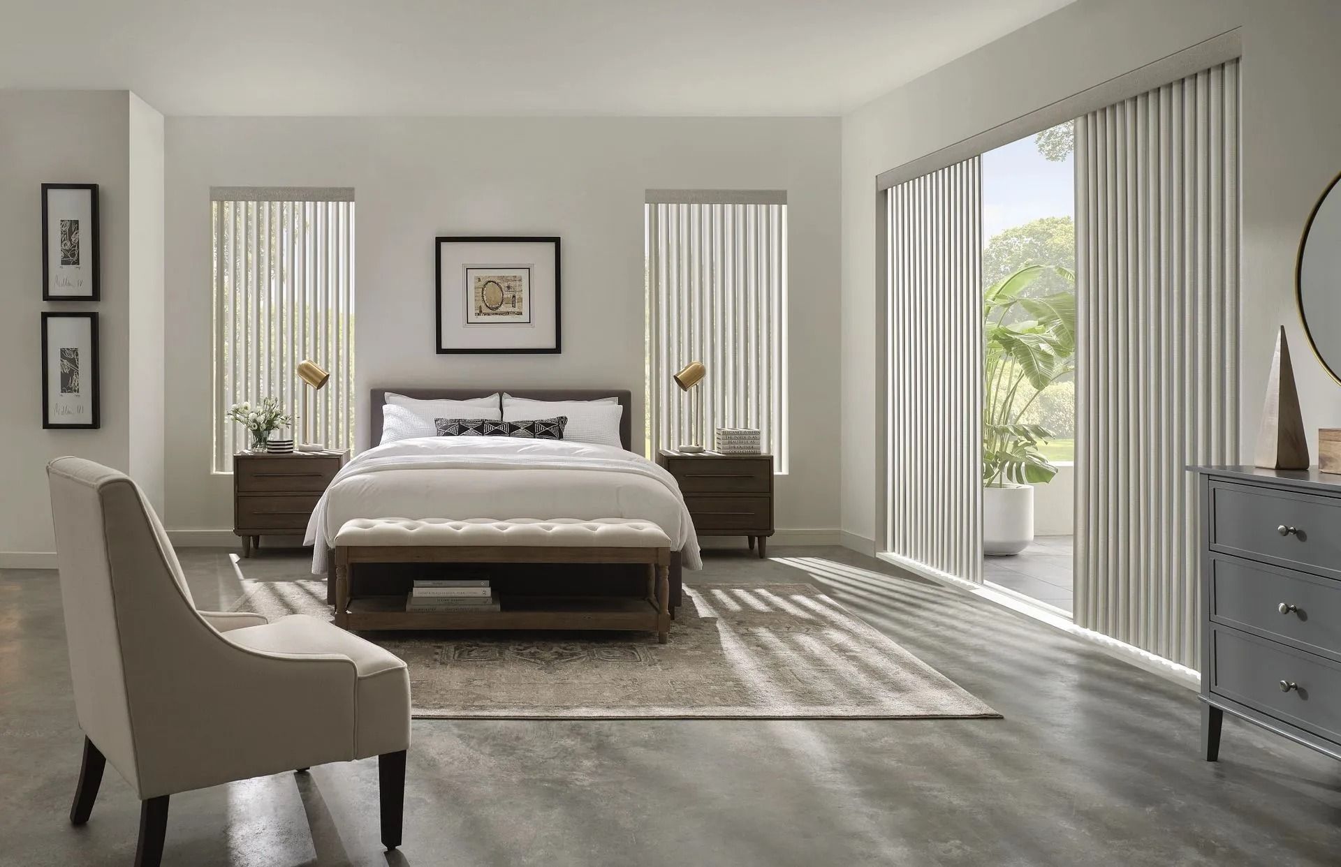 A modern bedroom featuring a bed with a bench, two nightstands, a beige armchair, and vertical blinds over doors and windows.