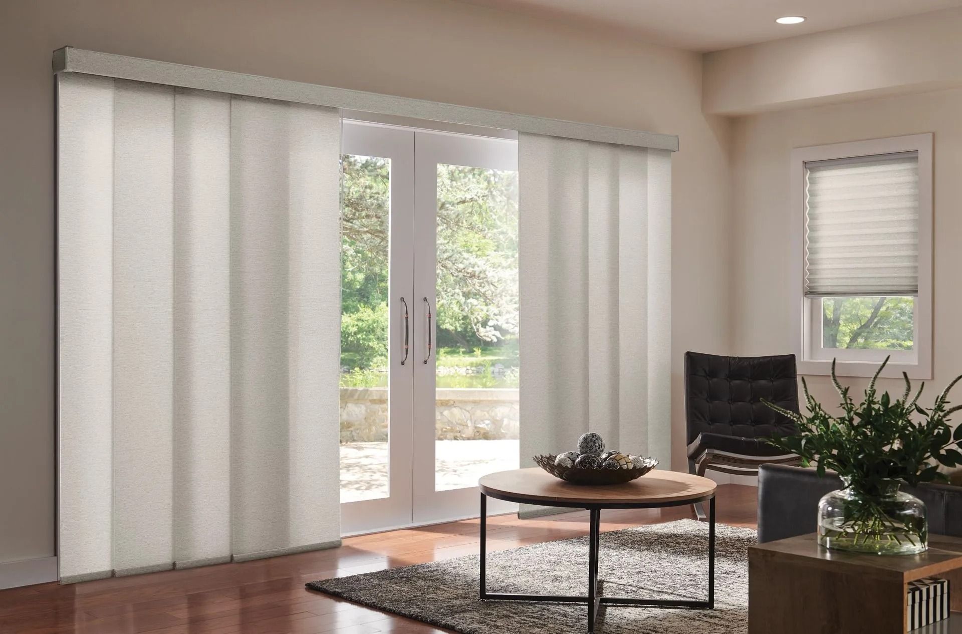Vertical sliding panel blinds covering a double glass door in a neutral, modern living room.