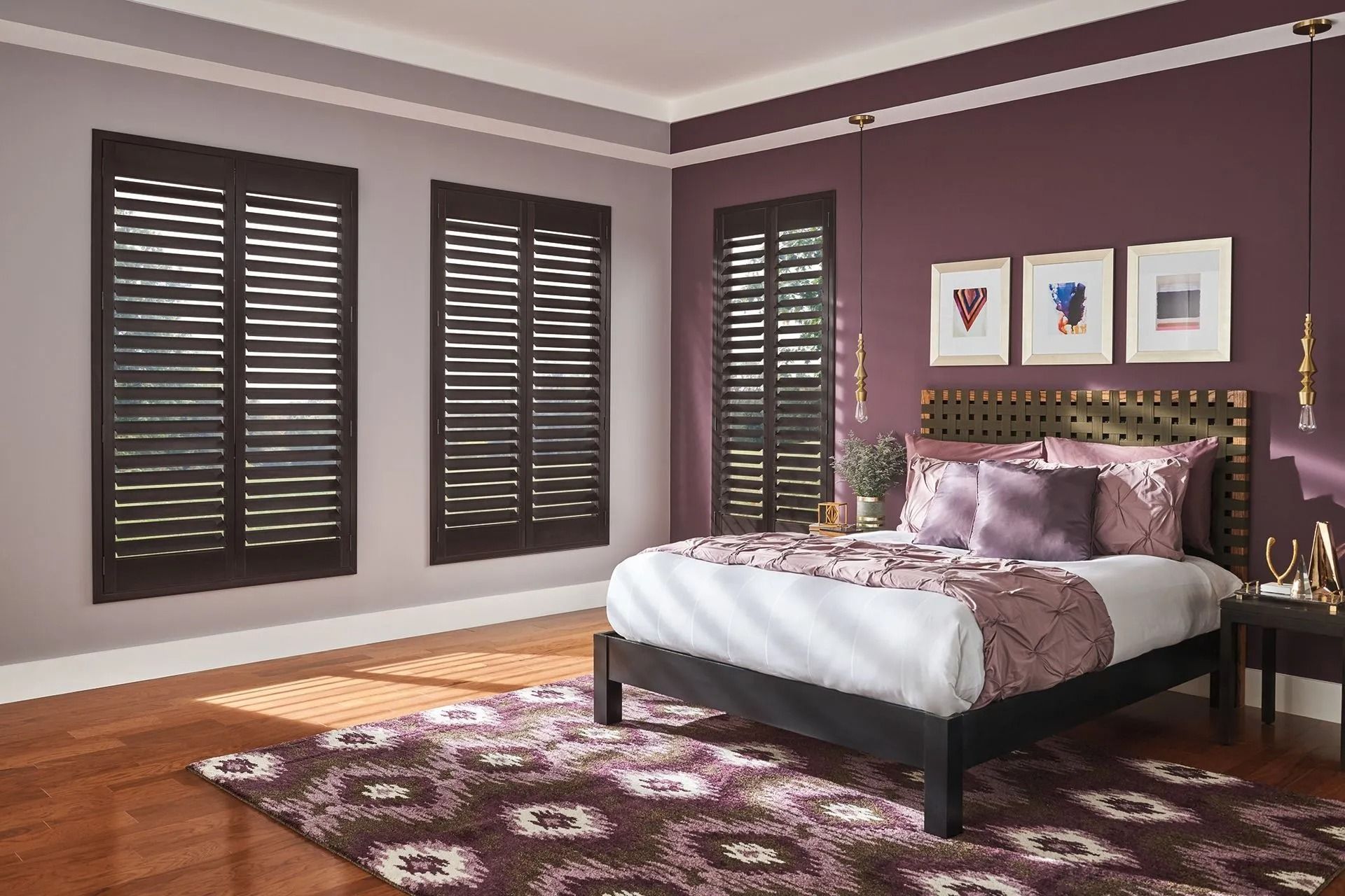 Bedroom with dark wood shutters on windows, a plum accent wall, and a bed with purple bedding and a patterned rug.